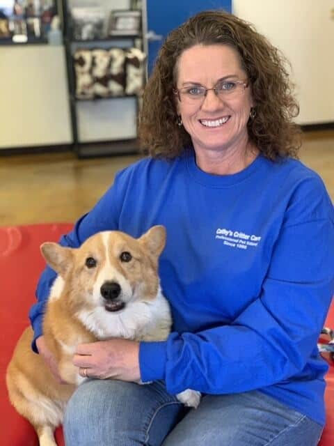 Woman in blue shirt with corgi dog indoors